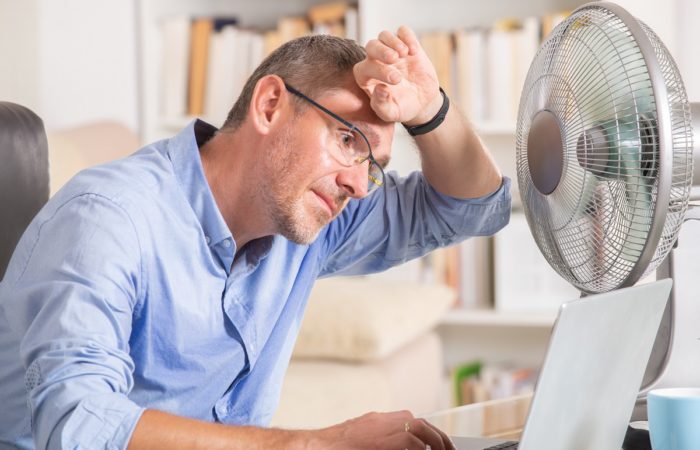 Man Suffers From Heat While Working In The Office And Tries To Cool Off By The Fan